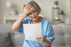 a woman placing a hand to her head while reading a document 