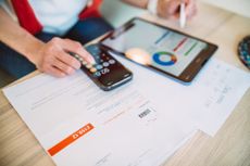 Woman managing home budget with the aid of financial app at home.