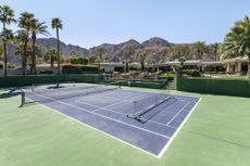 View of a full size tennis/pickleball court with mountain backdrop at a luxury, upscale estate in Indian Wells, California.