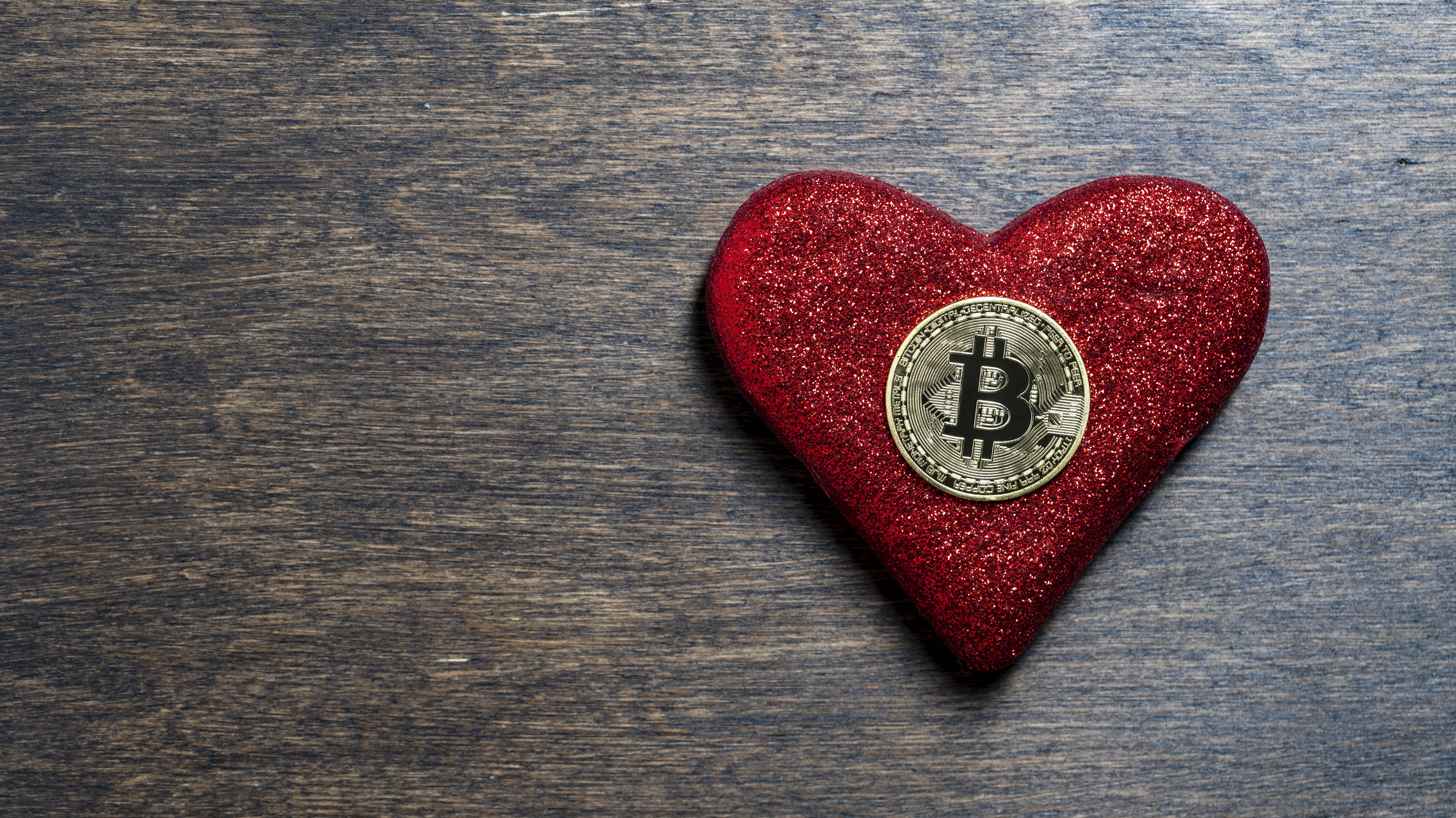 A bitcoin sits on a red velvet heart.