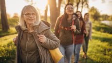 An older woman leads younger family members on a hike at sunset.